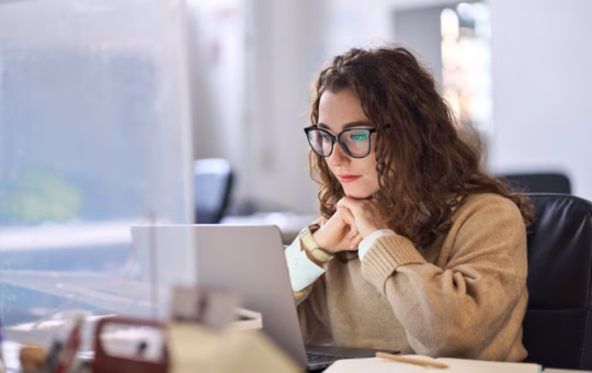 Image shows a woman working at her laptop
