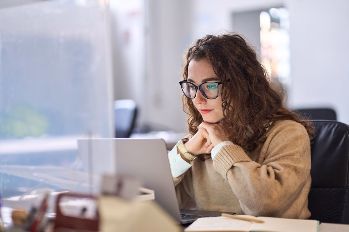 Image shows a woman working at her laptop